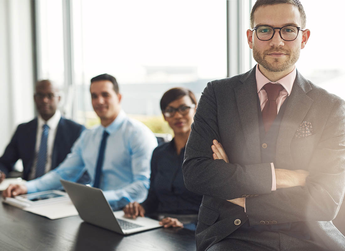 Meet the Pack - Professional and Welcoming Group at a Conference Table Faces the Camera, Team Leader Sitting on the Table with Arms Folded
